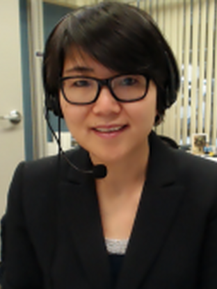 Photo of Yingting, she is wearing a black blazer and glasses and a headset with a microphone in it